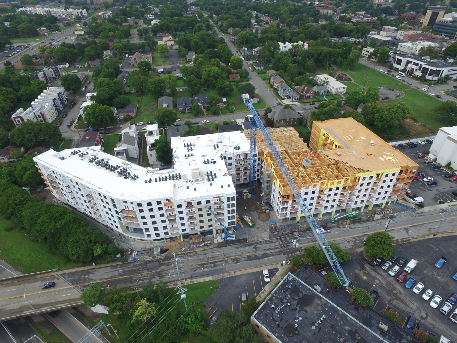 Aerial view of a multi-story building under construction beside a tower crane in a city