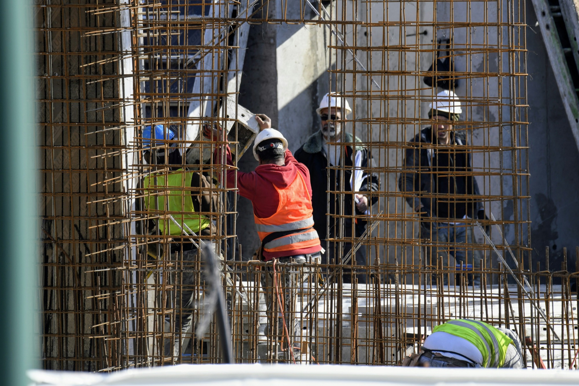 A crew placing rebar while two leads look on