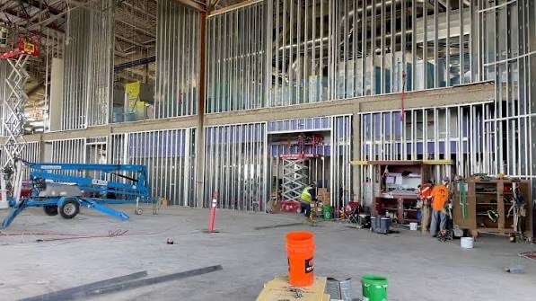 Metal stud walls filling a large open industrial interior, with lifts and a small crew