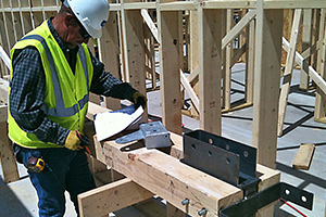 A carpenter checking a steel connector on a heavy timber beam