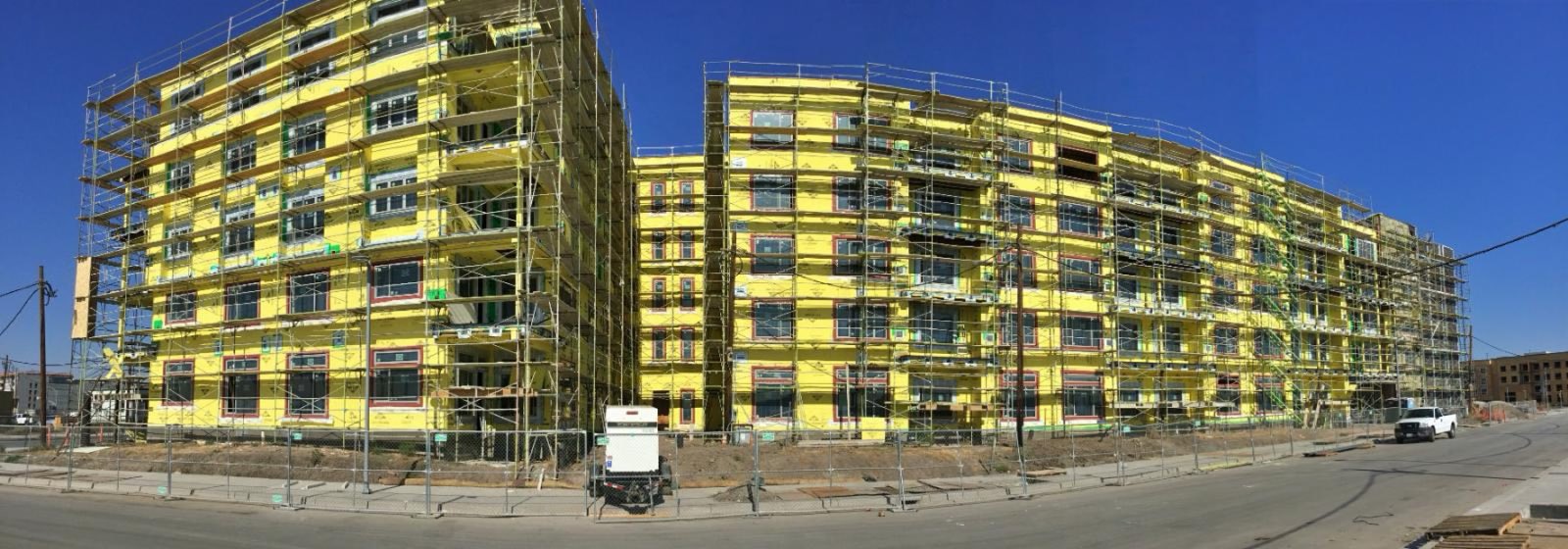 A wide view of multi-story buildings wrapped in sheathing and scaffold